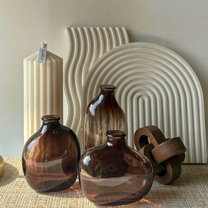 A collection of retro glass vases in various sizes with a geometric pattern, displayed alongside a lamp and a textured wall.
